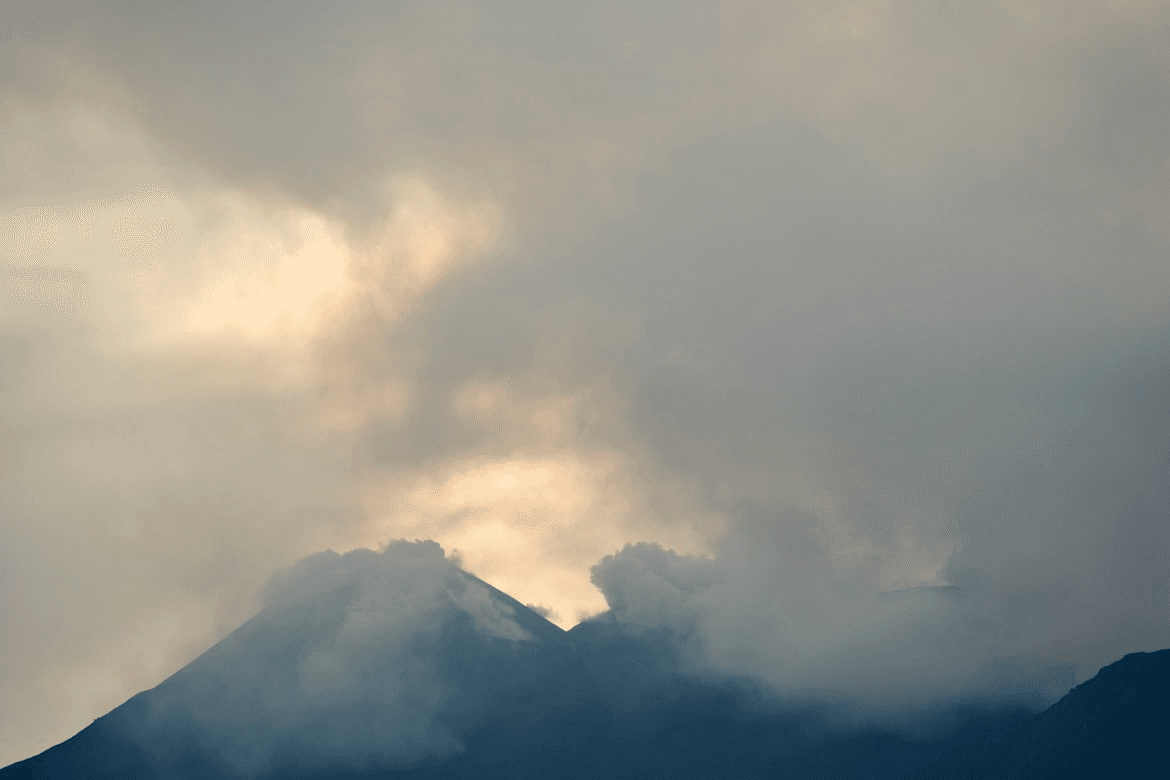 Mountain ridgeline obscured by atmospheric haze and cloud cover at dusk.